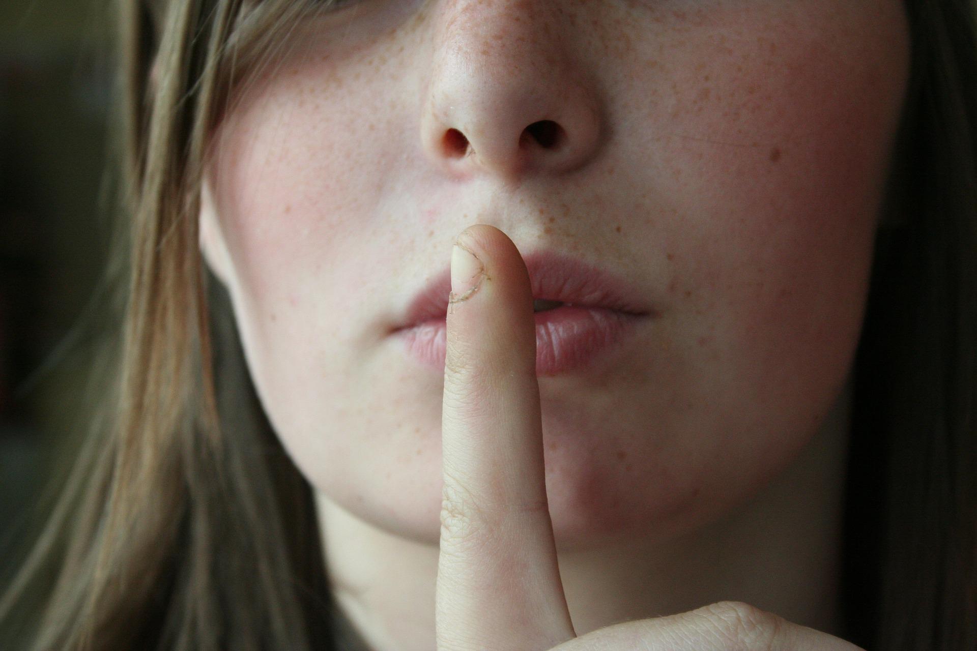 woman's face, with fingers on her lips